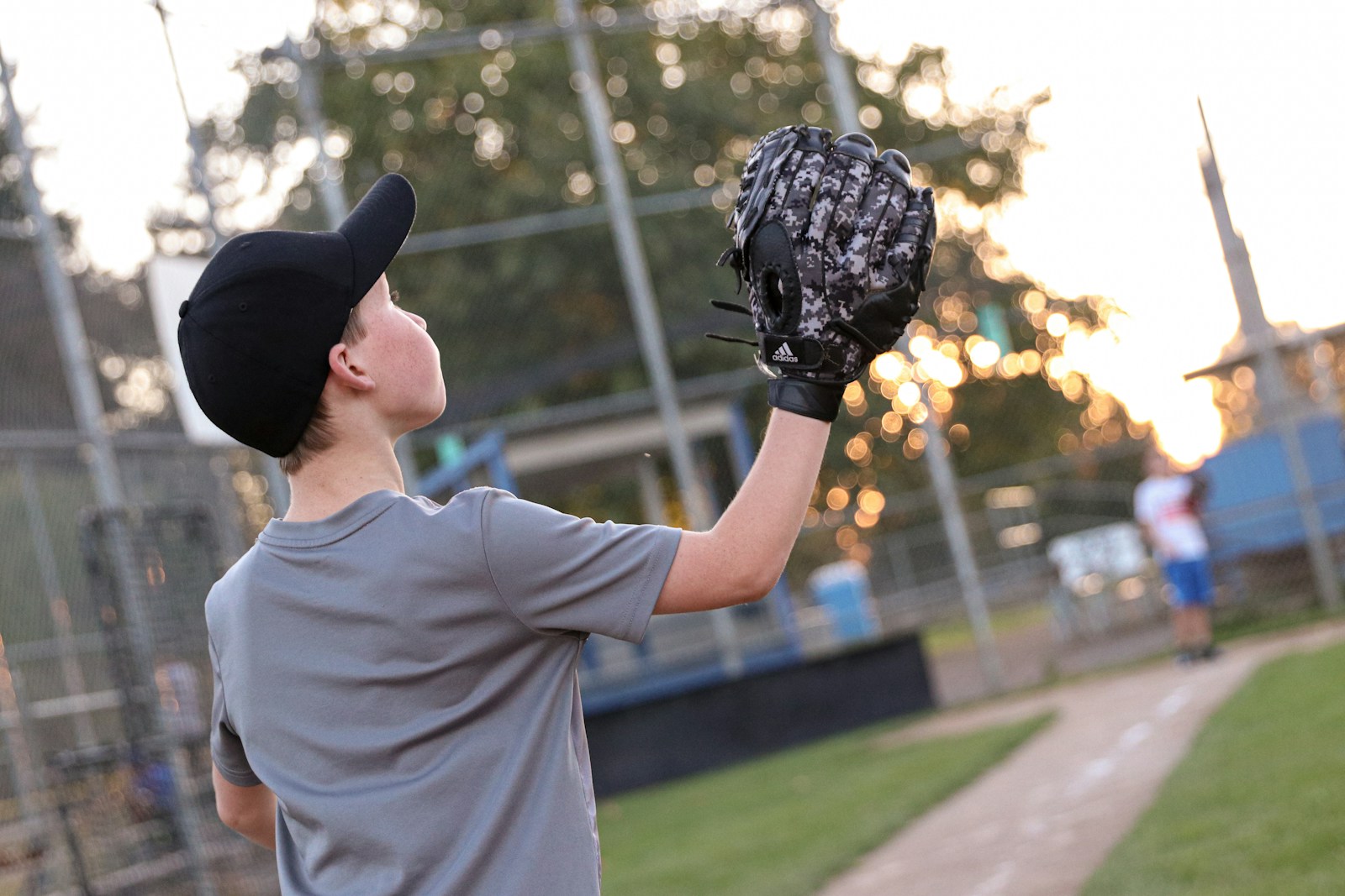 Youth outfielder tracking a fly ball near the foul line