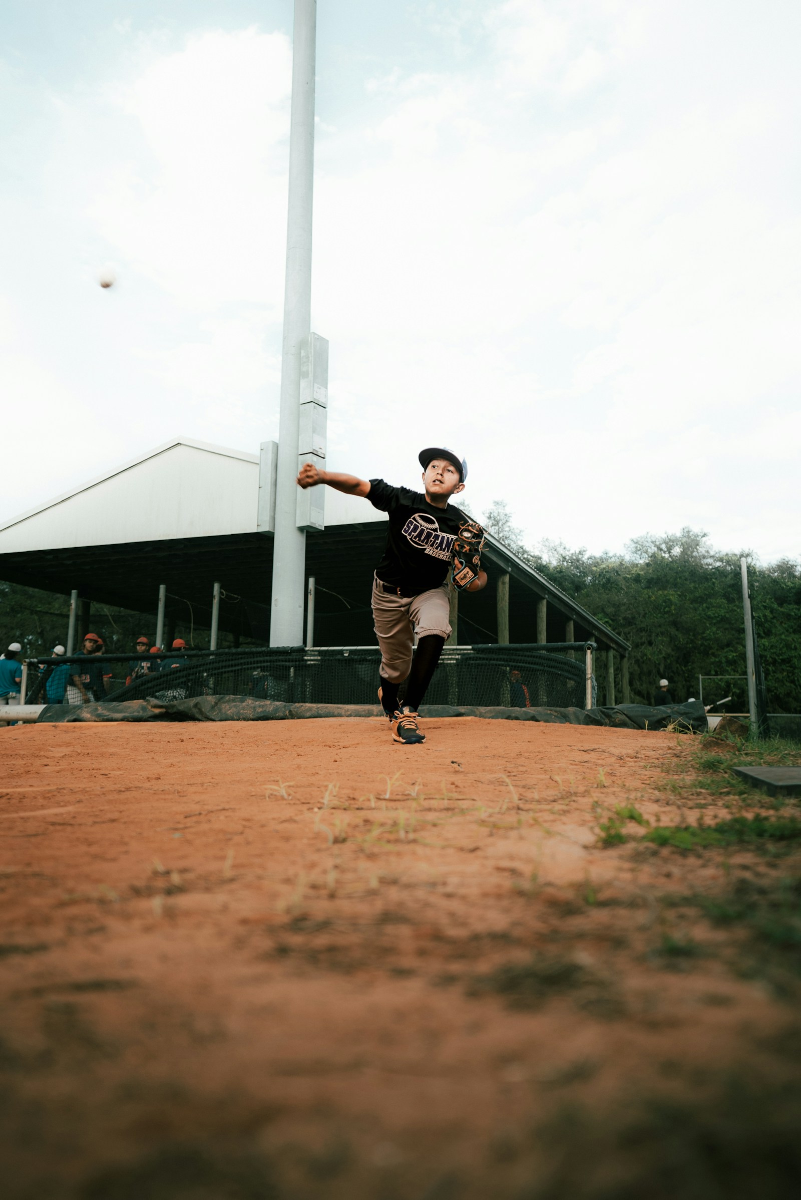 Youth pitcher delivering a pitch from the mound during a game