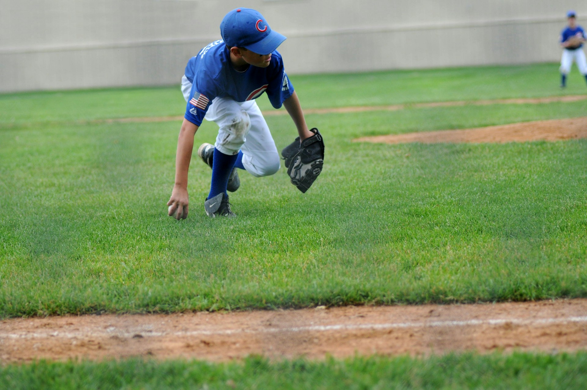 Youth infielder fielding a ground ball on the infield — photo by Unsplash